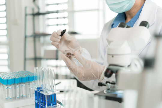 Female Laboratory Scientist Analyzing Samples with Pipette, Microscope and Laptop in Modern Research Laboratory