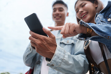 Asian couple using smartphone together outdoors for digital travel navigation