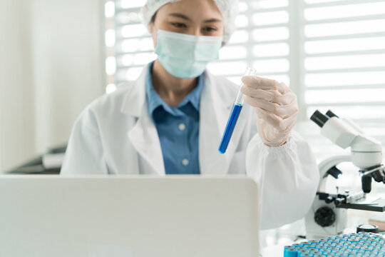 Female Laboratory Scientist Analyzing Samples with Pipette, Microscope and Laptop in Modern Research Laboratory