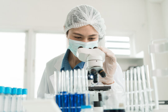 Female Laboratory Scientist Analyzing Samples with Pipette, Microscope and Laptop in Modern Research Laboratory