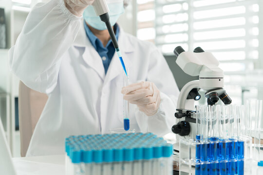 Female Laboratory Scientist Analyzing Samples with Pipette, Microscope and Laptop in Modern Research Laboratory