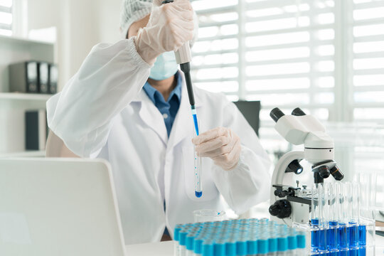 Female Laboratory Scientist Analyzing Samples with Pipette, Microscope and Laptop in Modern Research Laboratory