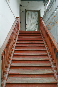 Rustic wooden stairs with red paint and balustrade leading up