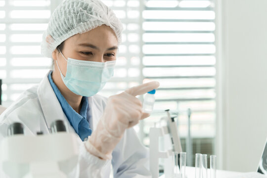 Female Laboratory Scientist Analyzing Samples with Pipette, Microscope and Laptop in Modern Research Laboratory