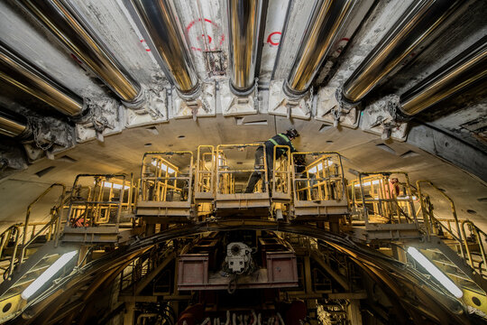 A construction worker inspects a drilling machine inside a tunnel