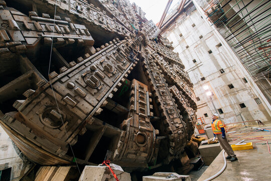 Construction white workers inspect massive tunnel boring machine