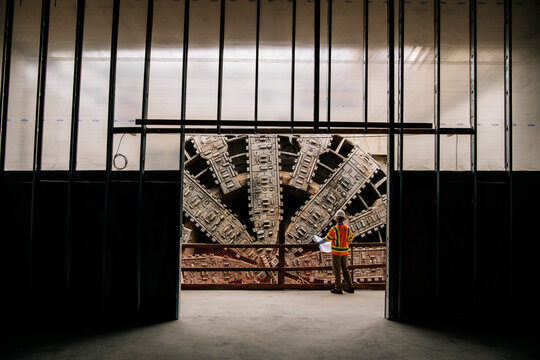 A construction white worker inspects a large tunnel boring machine