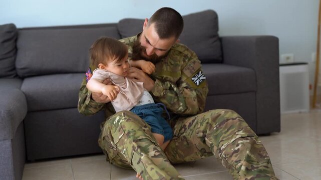 English male soldier in military uniform returning home to family - Father hugging baby son - Homecoming, happiness and love concept	