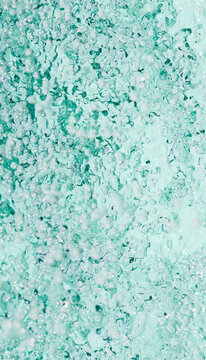 Close-up of vibrant aqua blue water splash with bubbles in motion