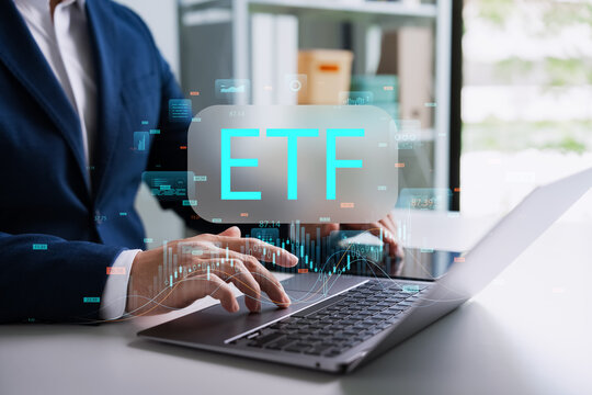 A professional businessman analyzes ETF data on a modern laptop with a futuristic glowing financial chart hologram in the office. This smart technology represents modern digital trading investment.