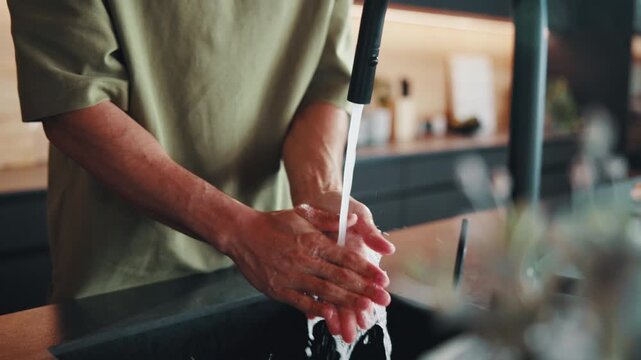Man, washing hands and water in kitchen for cleaning, good hygiene practice and dirt removal. Person, faucet and rinsing in home for wellness, bacteria prevention and dermatology with self care