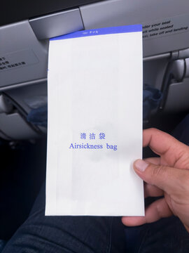 Hand holding an airsickness bag on an airplane
