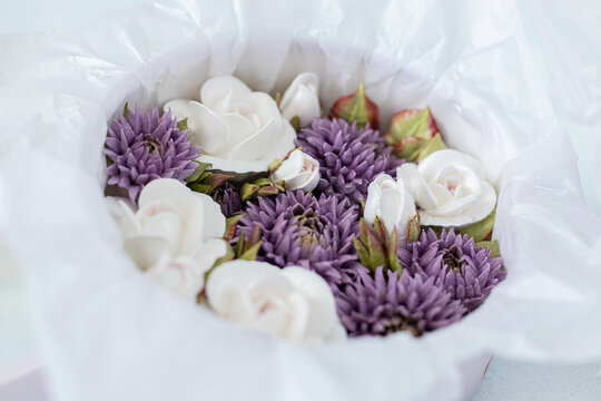 Floristry from Zephyr. White roses and purple chrysanthemums arranged in a round box with soft tissue paper, creating an elegant floral display for gifting or decoration