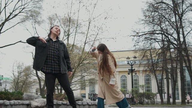 Close up of two people dancing together outdoors in public park setting. man and woman move fluidly performing coordinated dance steps with expressive body language while interacting