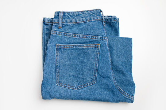 Blue indigo jeans on white background, top view with space for text. Fashionable jeans made of natural cotton, wardrobe item. Fashion and style concept, shopping