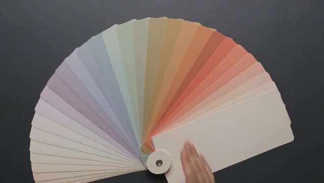 Top view of designer opening a color swatch fan deck for interior palette selection