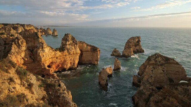 View of Ponte da Piedade in Lagos, Algarve, Portugal, with soft morning sky, ocean cliffs and sea stacks.