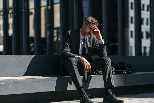 Stressed businessman suffering from headache on city bench