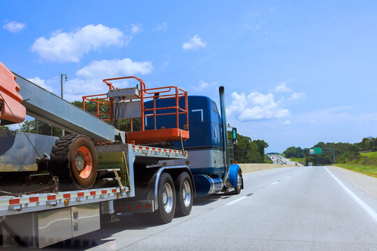 Large truck with construction tools drives on American interstate highway,