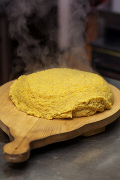 Soft steaming freshly made polenta on wooden board in professional artisan kitchen