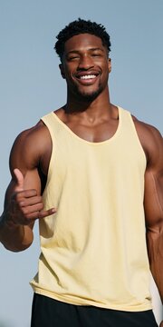 Smiling athletic man in a yellow tank top making a shaka gesture outdoors for fitness and lifestyle banner or advertising background