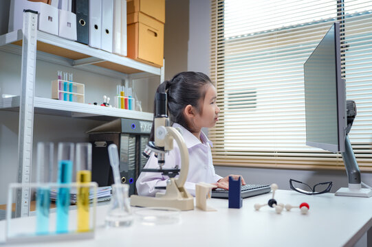 Asian girl student in lab coat using computer in science laboratory for stem education and school learning concepts