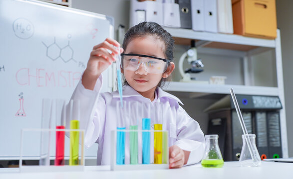 Young asian girl conducting science experiment with colorful liquids in classroom laboratory for education and stem learning concept