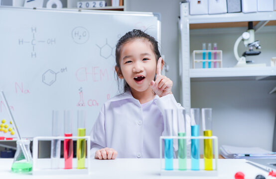 Asian girl scientist raising finger with idea during science experiment in school laboratory for stem education and chemistry learning concepts