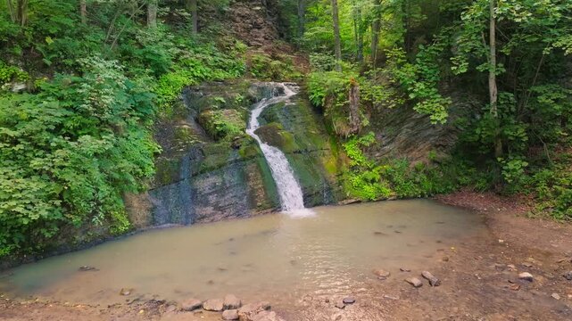 Hurkalo Waterfall. Aerial drone view approaching the scenic waterfall surrounded by lush green forest in the Carpathian Mountains, Lviv Region, Ukraine, summer.