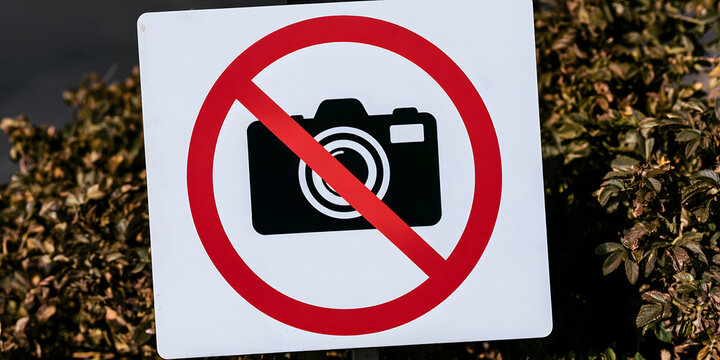 A sign with a black camera icon encircled in a red circle prohibits photography.