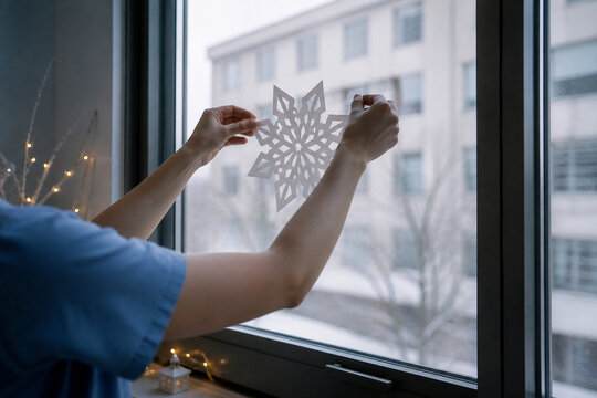 Faceless hands taping a white paper snowflake onto a hospital ward