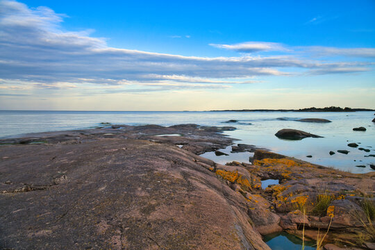 Rocky Skerry Coast by Calm Sea Under Blue Evening Sky