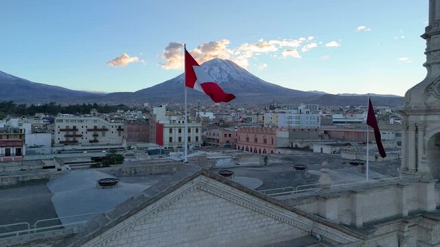 Slow motion of the Peruvian flag waving gently with Misti volcano and sunrise sky in the background, Arequipa, Peru