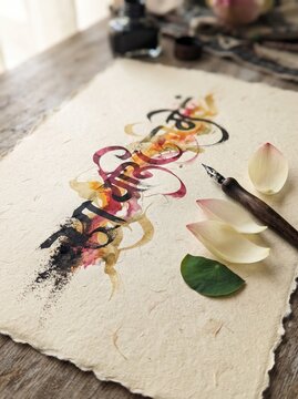 Devanagari calligraphy artwork with ink pen, petals and leaves on handmade paper for Hindi or Sanskrit typography concept