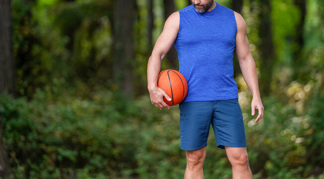 Guy has sport motivation, cropped view. Sport and hobby. Sport and recreation. Active lifestyle. Summer activity. Man with basketball ball in forest. Professional basketball player training outdoor