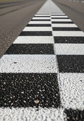 Obraz premium Ground level view of a checkered stripe painted across a professional speedway, focusing on the rough texture of the paved surface, pavement, speedway, outdoor