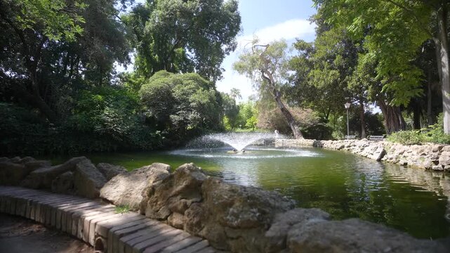 View of fountain and pond in Parque de Mari&shy;a Luisa on a sunny day, Seville, Andalusia, Spain