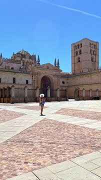 young woman walking across cathedral square in Zamora, Castile and Leon, Spain
