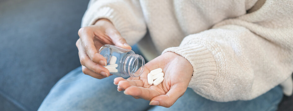 Sick asian young woman, girl holding tablet pill on hand pouring drug from medication bottle, painkiller medicine from stomach pain, head ache, pain for treatment, take drug or vitamin, health care.