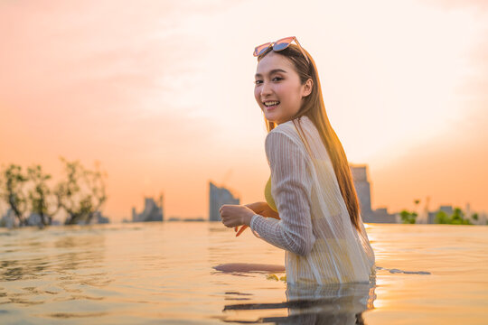 Young cheerful woman laughing at luxury rooftop sunset, embracing pure summer freedom, joy, travel vitality, and wellness lifestyle while relaxing on scenic city holiday getaway.