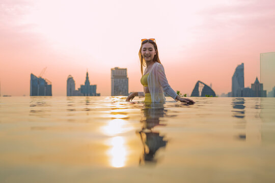 Young cheerful woman laughing at luxury rooftop sunset, embracing pure summer freedom, joy, travel vitality, and wellness lifestyle while relaxing on scenic city holiday getaway.