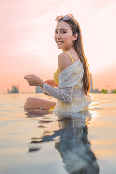 Young cheerful woman laughing at luxury rooftop sunset, embracing pure summer freedom, joy, travel vitality, and wellness lifestyle while relaxing on scenic city holiday getaway.
