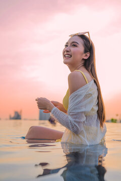 Young cheerful woman laughing at luxury rooftop sunset, embracing pure summer freedom, joy, travel vitality, and wellness lifestyle while relaxing on scenic city holiday getaway.