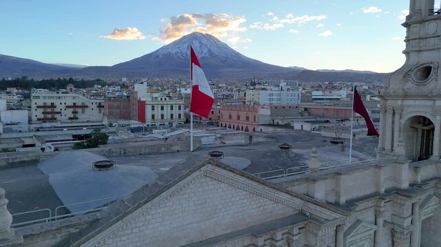 Aerial view of Arequipa Cathedral and the Peruvian flag waving at sunrise, Peru
