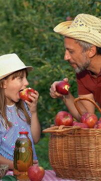 Father and Daughter Sharing Fresh Apples During Harvest. Loving family moment as a farmer shares his fruit with his daughter in warm September sunlight.