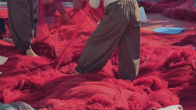 Workers standing and sorting red fishing nets at fishing port in Central Vietnam