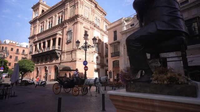 View of horse and carriage passing Francisco Palacios El Pali statue on a sunny day, Seville, Andalusia, Spain