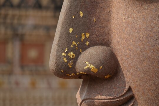 Close up of Buddha statue nose with gold leaf