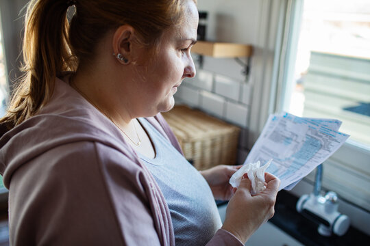 Concerned woman reading utility bills in home kitchen