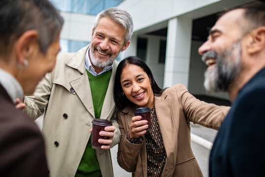 Diverse coworkers laughing during coffee break outside office building